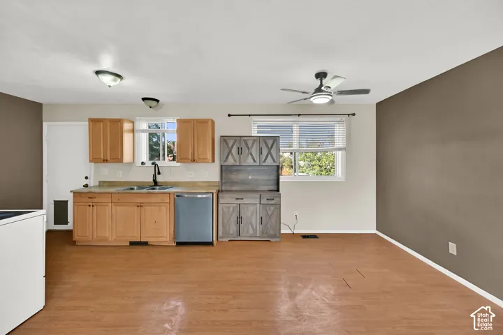 Kitchenette featuring light wood-finish cabinetry, stainless steel dishwasher, and a window above the sink