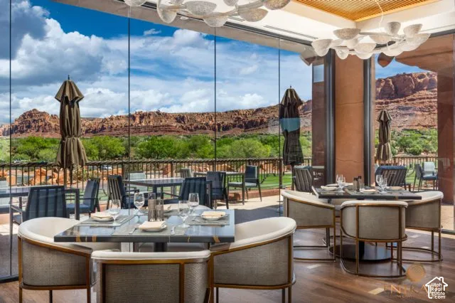 Expansive outdoor dining area with glass panel walls, showcasing a mountain landscape