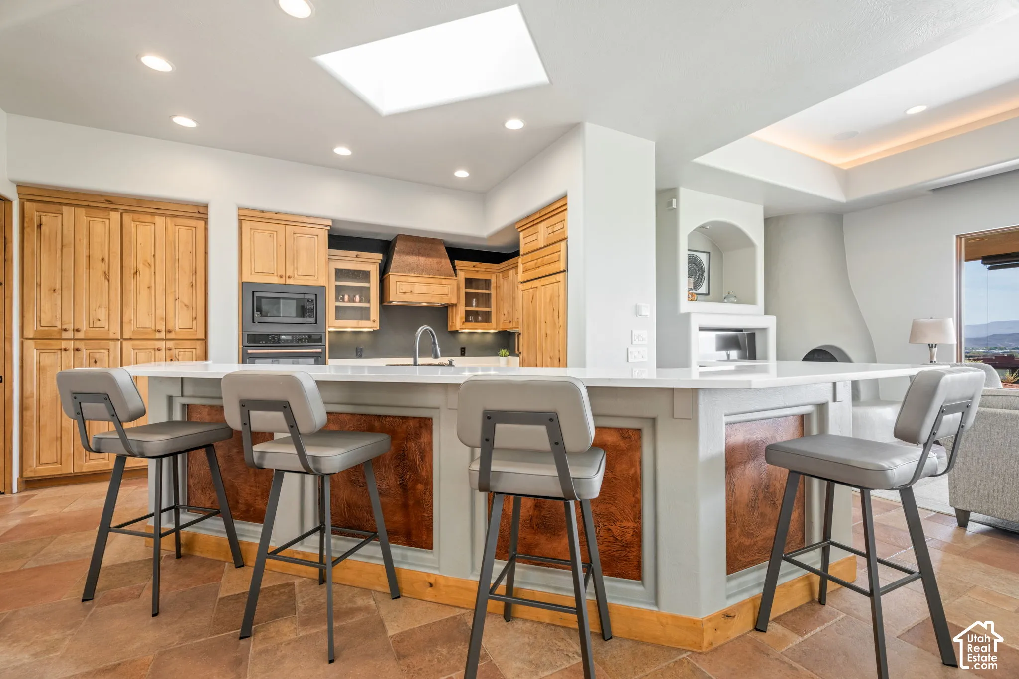 Kitchen featuring a peninsula with a light-colored countertop, integrated appliances, wood-finish cabinetry, recessed lighting, and a skylight