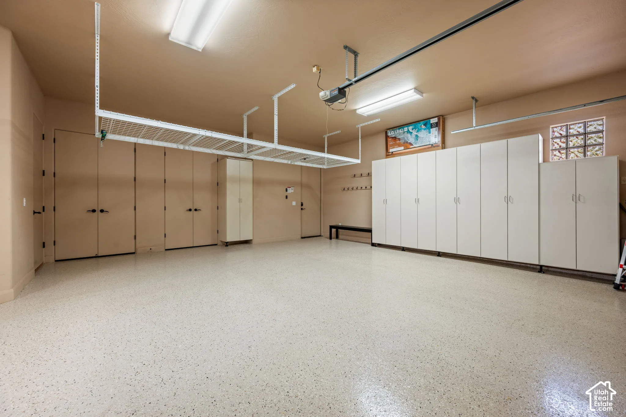 Epoxy-coated flooring, extensive built-in cabinetry, overhead storage racks, transom window with glass blocks, and multiple ceiling-mounted light fixtures