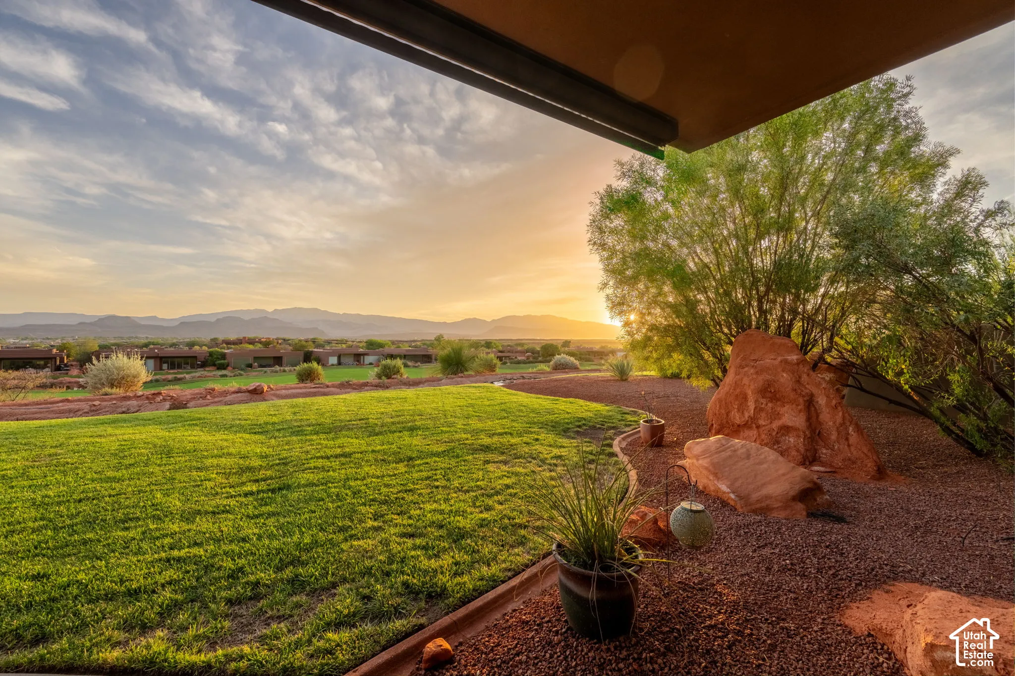 Expansive lawn with natural rock features, established desert landscaping, and distant mountain scenery