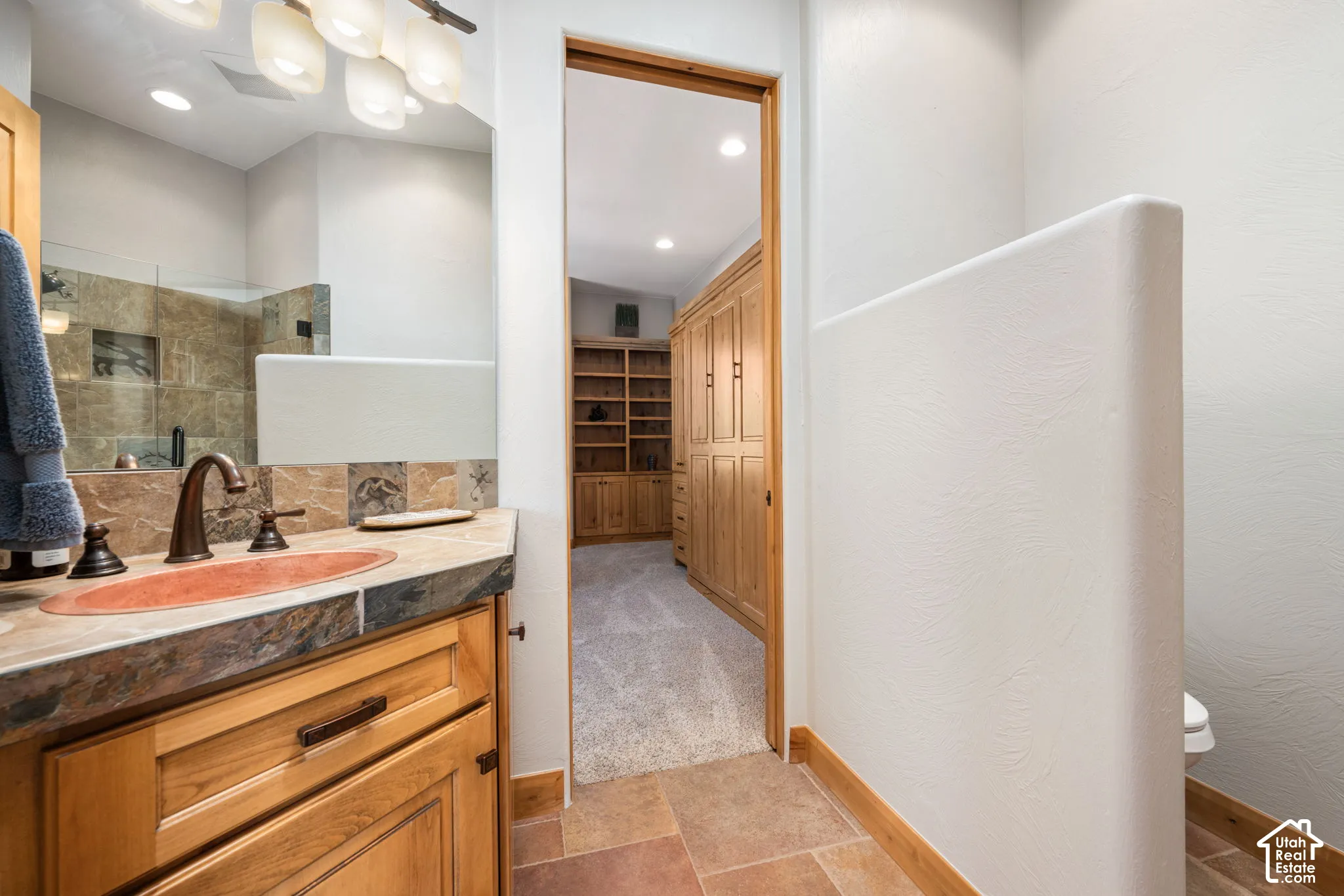 Custom vanity with a natural stone countertop, vessel sink, and oil-rubbed bronze fixtures
