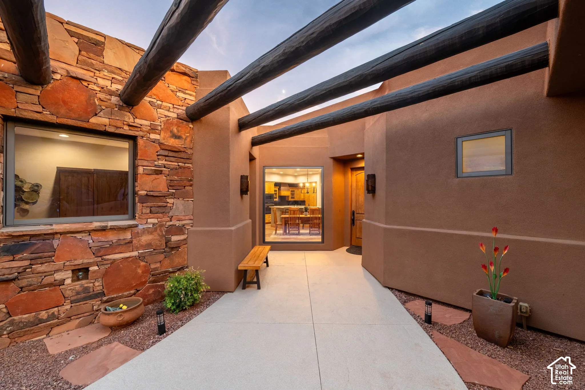 Stone veneer exterior with exposed timber beams, stucco finishes, and a solid wood entry door