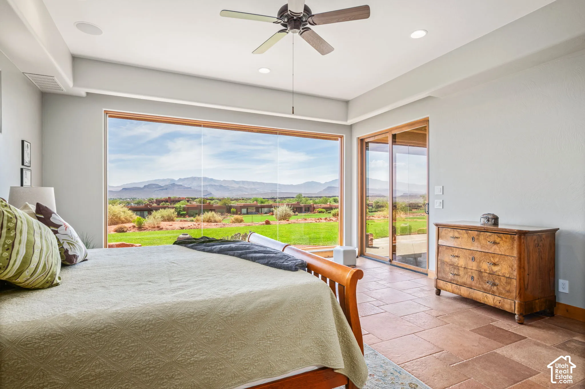 Expansive window wall, glass sliding doors, recessed lighting, ceiling fan, and large format stone tile flooring