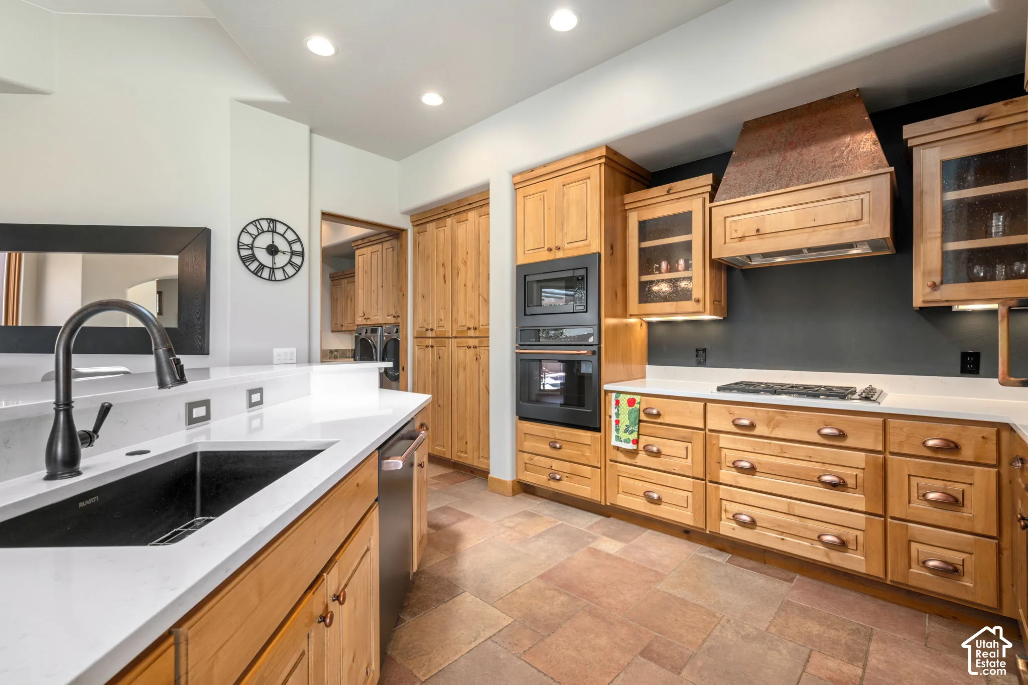 Kitchen featuring light wood cabinetry, white countertops, a black undermount sink, built-in double ovens, and tile flooring