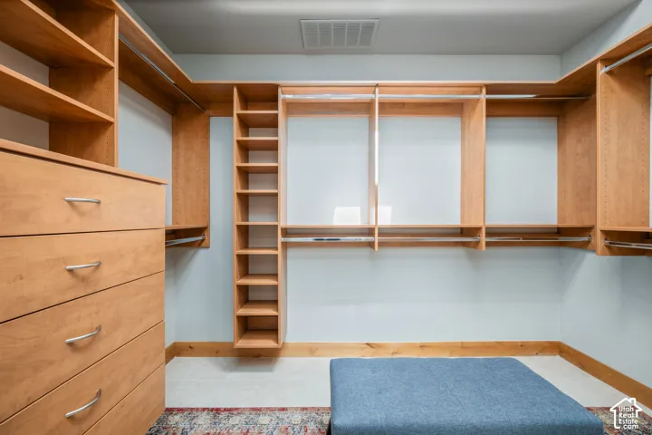 Custom built-in wood-finish shelving, integrated drawers with brushed nickel hardware, and multiple hanging rods provide ample storage