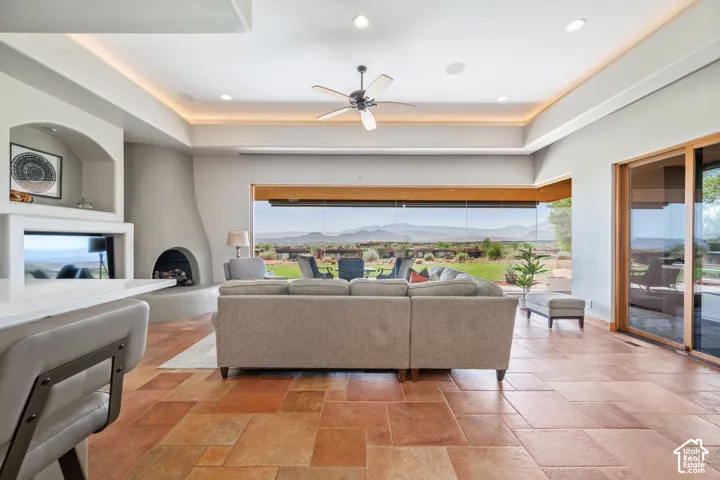 Spacious living area featuring extensive tile flooring, a built-in fireplace, a ceiling fan, and large sliding glass doors