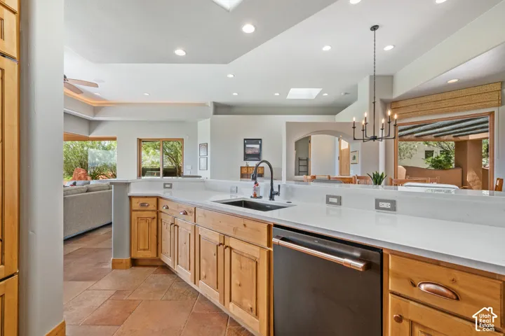 Kitchen featuring light wood cabinetry, white countertops, built-in dishwasher, and a black faucet