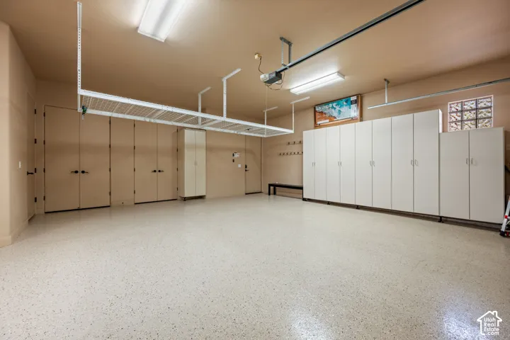 Epoxy-coated flooring, extensive built-in cabinetry, overhead storage racks, transom window with glass blocks, and multiple ceiling-mounted light fixtures