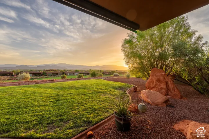 Expansive lawn with natural rock features, established desert landscaping, and distant mountain scenery