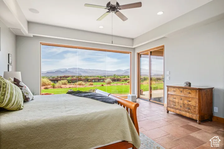 Expansive window wall, glass sliding doors, recessed lighting, ceiling fan, and large format stone tile flooring