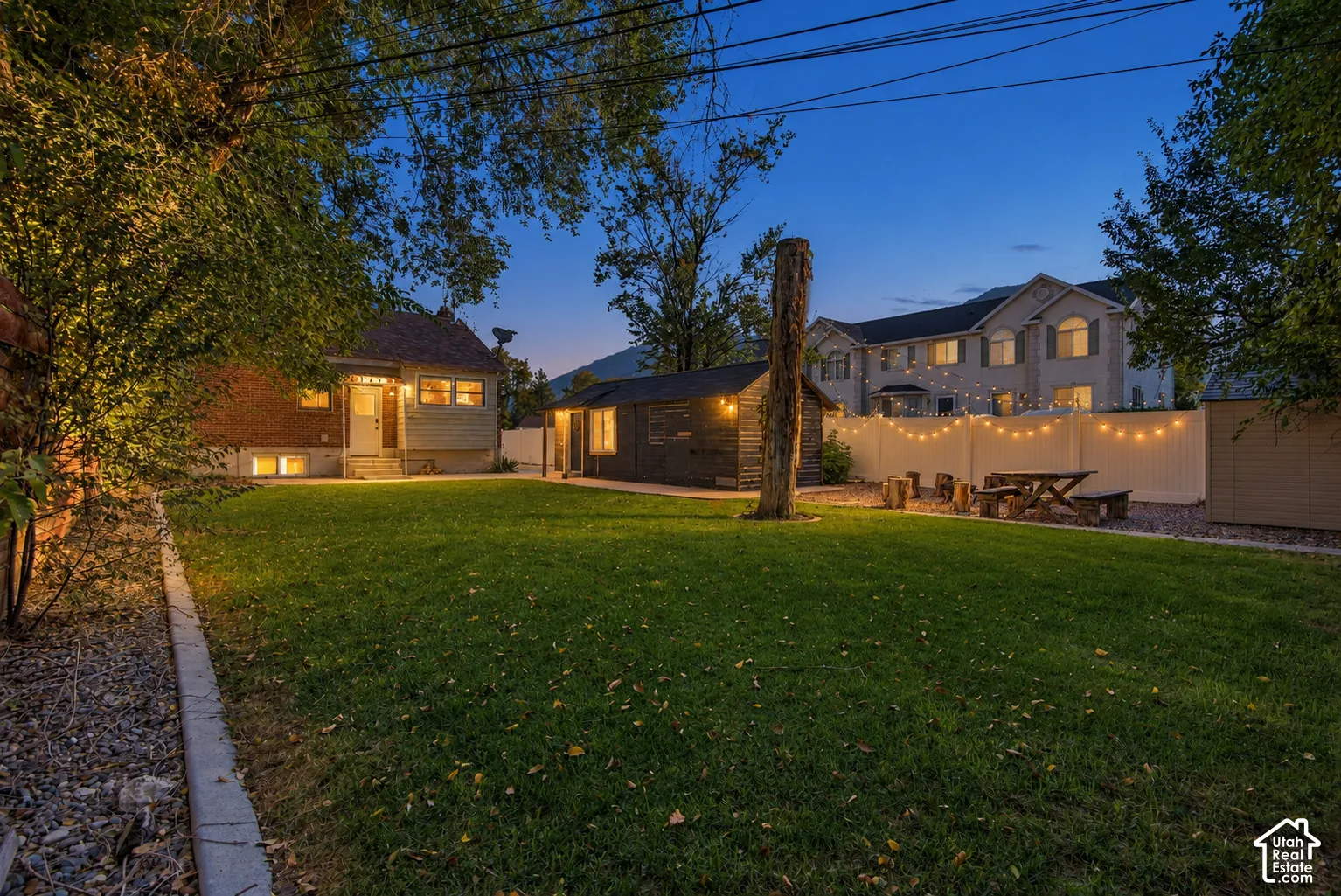 Expansive backyard featuring a manicured lawn, established trees, and a privacy fence