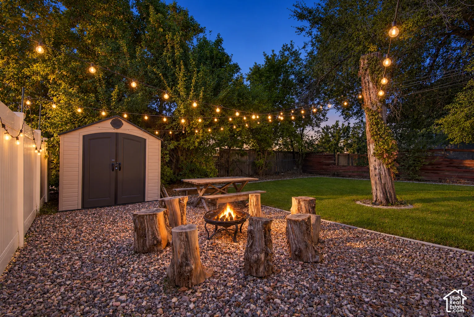 Expansive backyard featuring a fire pit, gravel ground cover, manicured lawn, and a storage shed