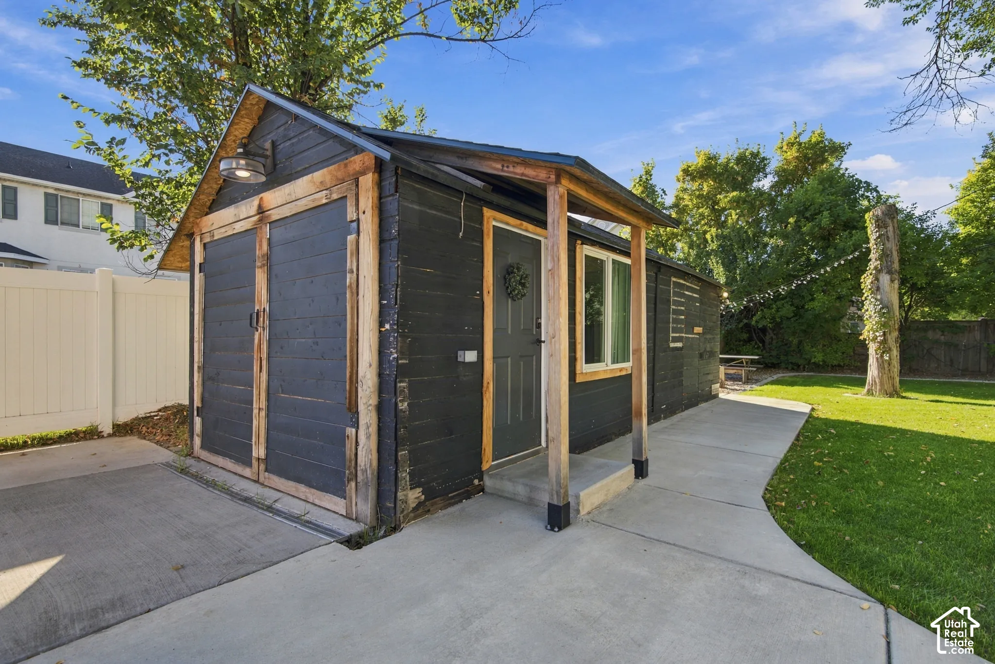 Detached outbuilding with an attached single-car garage, concrete driveway, and a covered entry