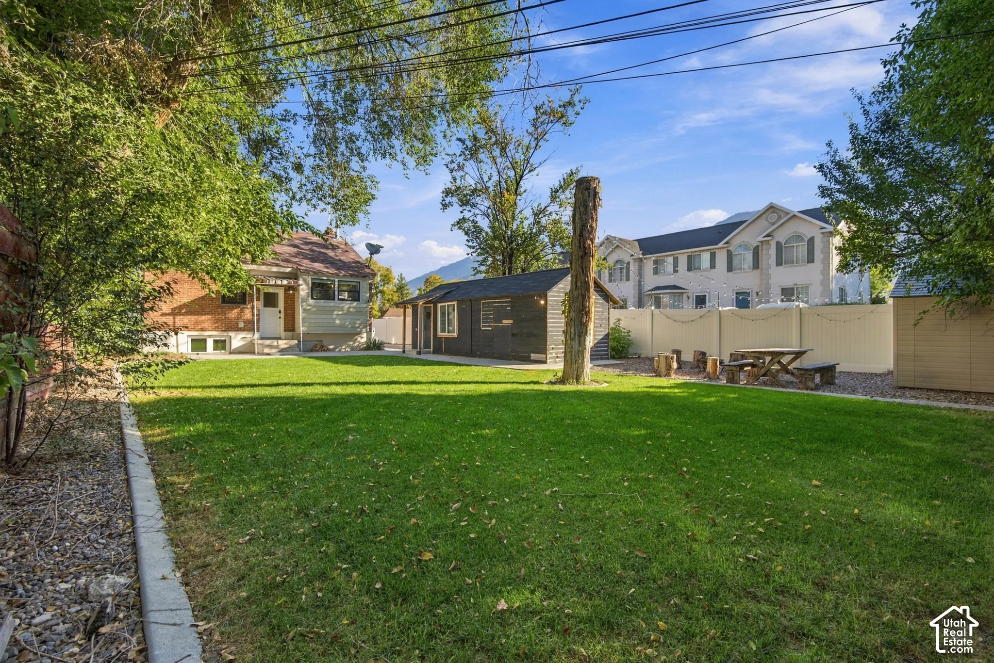 Expansive green lawn, established trees, detached shed, and fenced perimeter