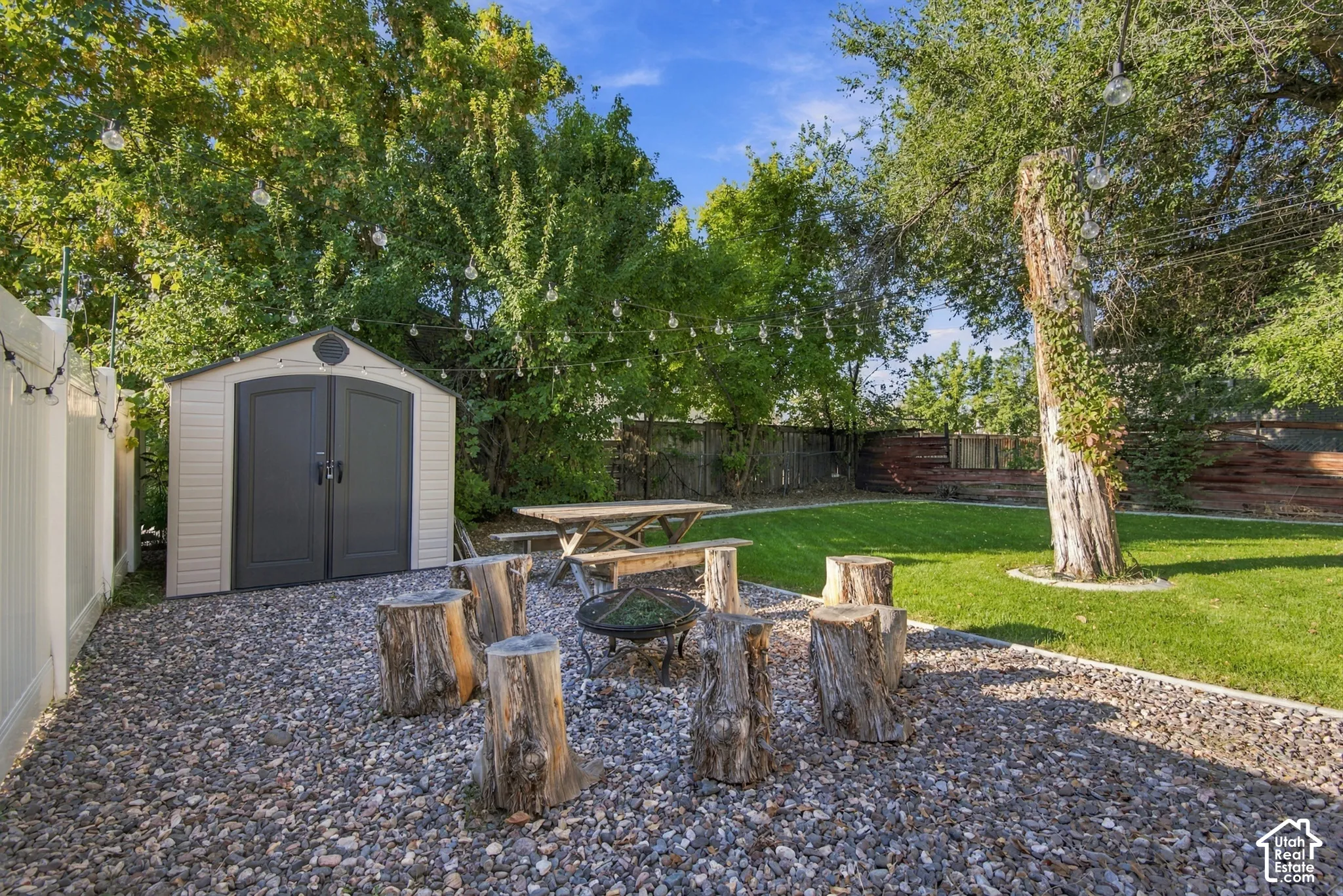 Expansive backyard featuring a manicured lawn, gravel patio area, and mature trees