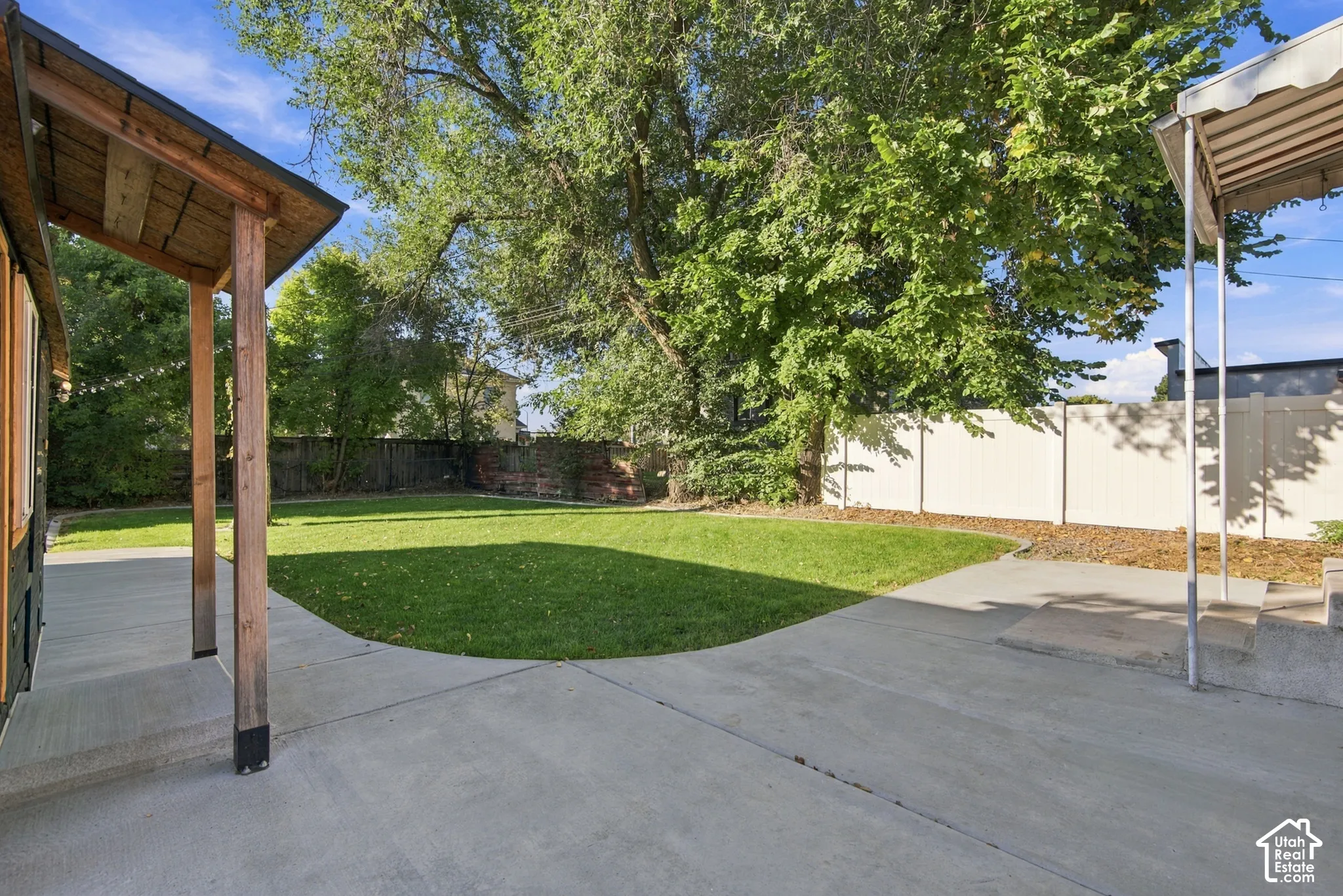 Expansive concrete patio with a covered porch featuring wood posts and a wood plank ceiling