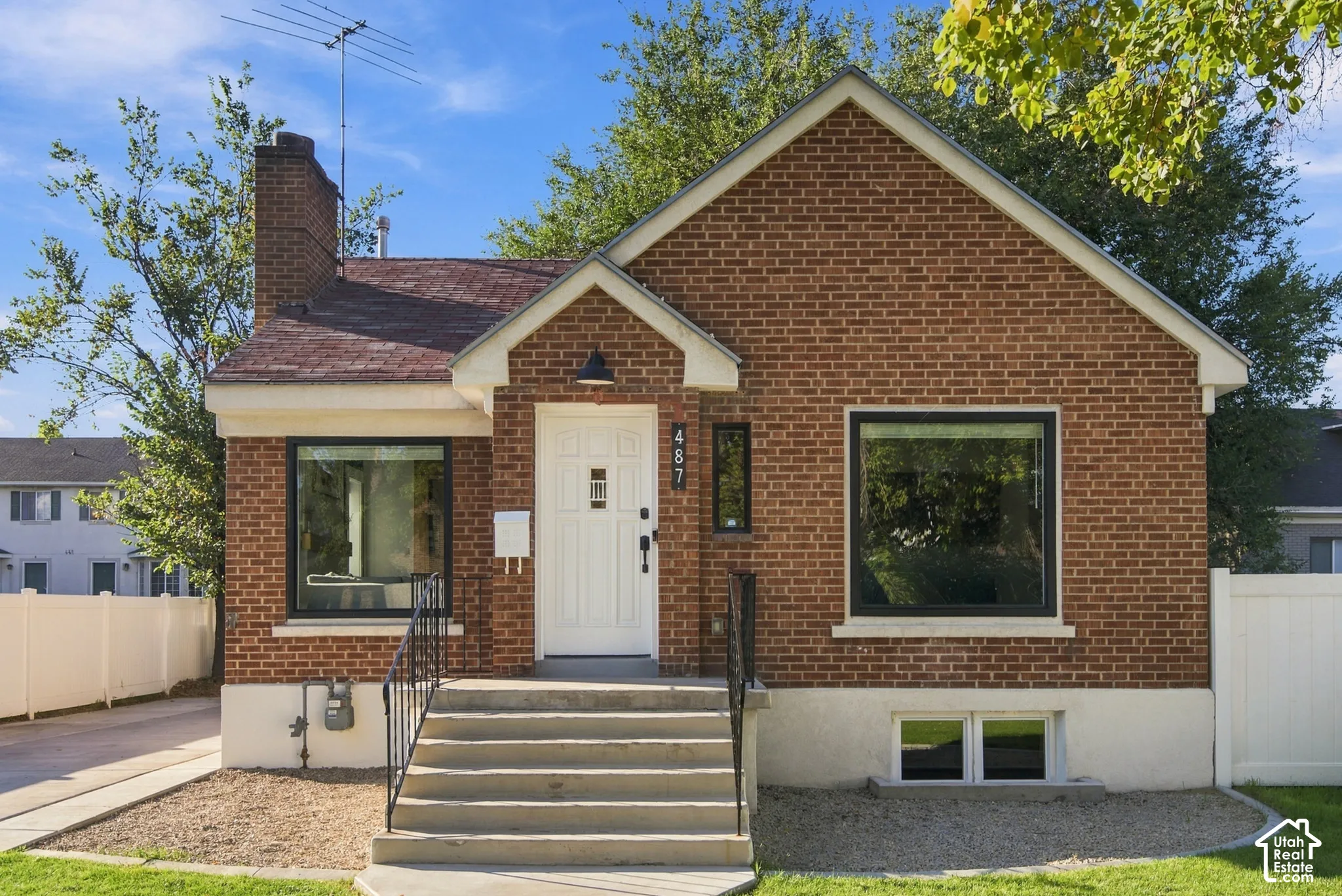 Brick exterior with a prominent chimney, dark-framed windows, and a white entry door