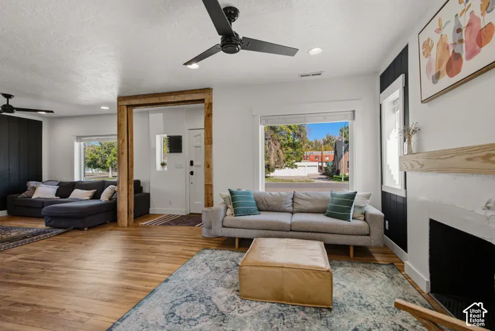 Wood-finish flooring throughout, modern black ceiling fans, and a decorative fireplace with a light wood mantle