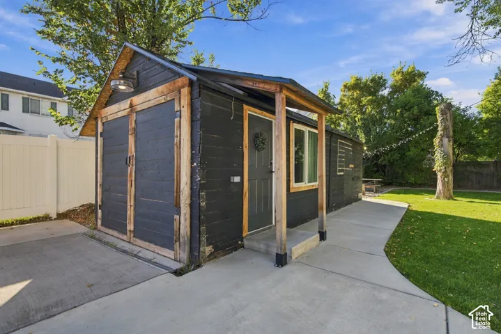 Detached outbuilding with an attached single-car garage, concrete driveway, and a covered entry