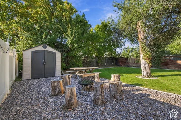 Expansive backyard featuring a manicured lawn, gravel patio area, and mature trees
