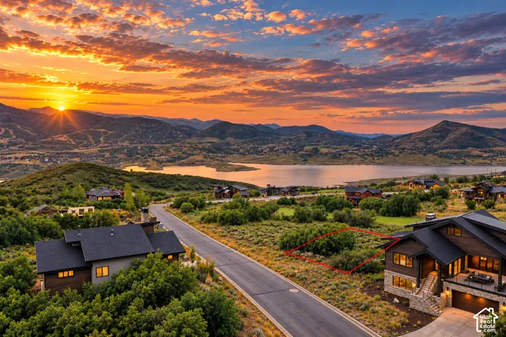 Terraced lot with a paved street, surrounded by natural landscaping, featuring expansive mountain and lake scenery