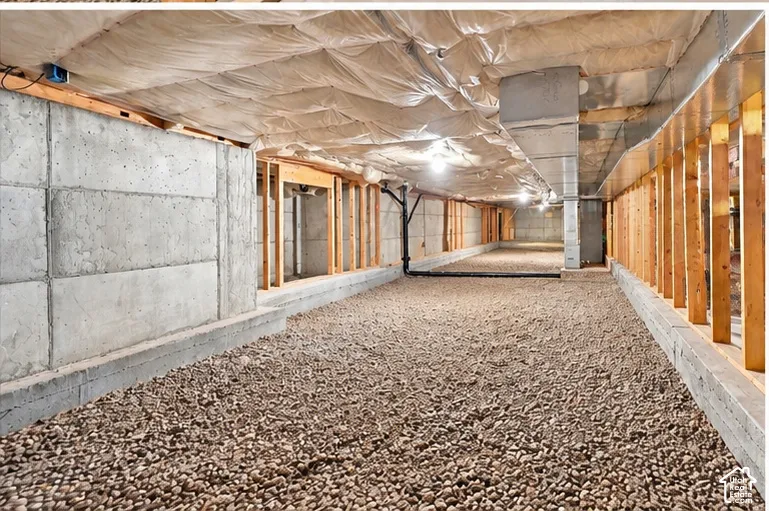 Unfinished crawl space featuring poured concrete foundation walls, stone gravel ground cover, insulated ceiling joists, and exposed wood framing