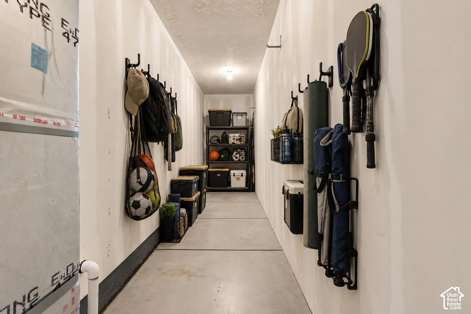 Utility space featuring concrete flooring, drywall finish, and wall-mounted storage hooks
