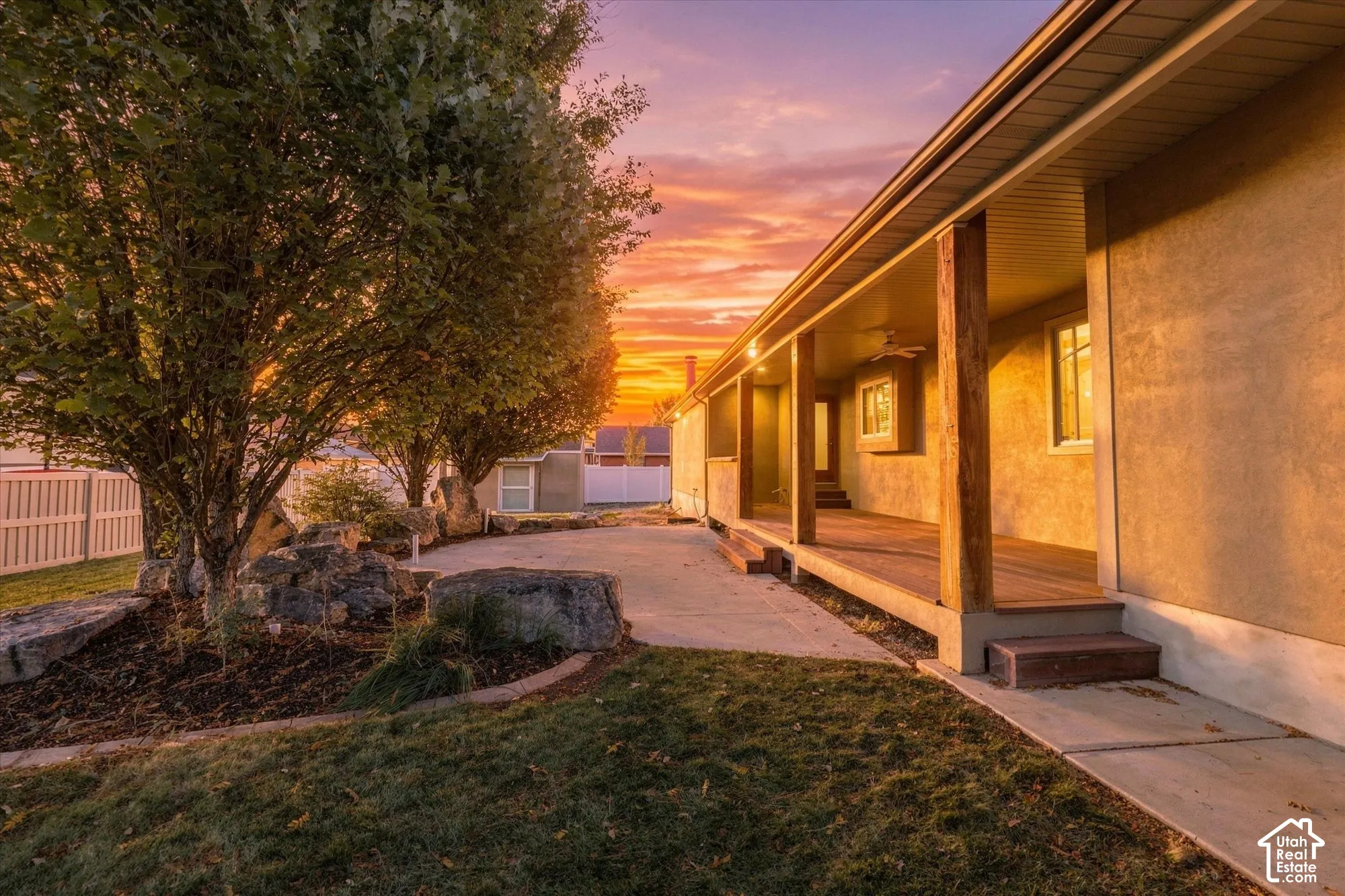 Covered wood-deck porch featuring timber support posts, concrete patio, and landscaped rock garden