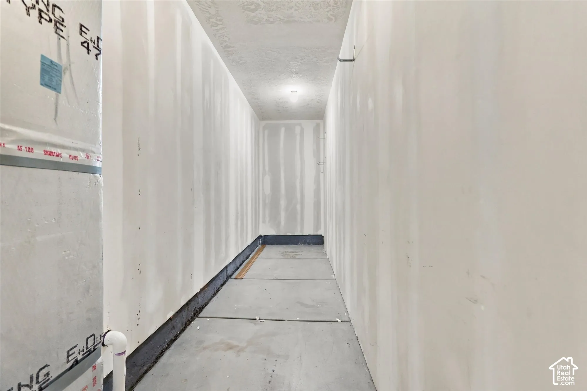 Unfinished utility space featuring concrete flooring and taped drywall panels