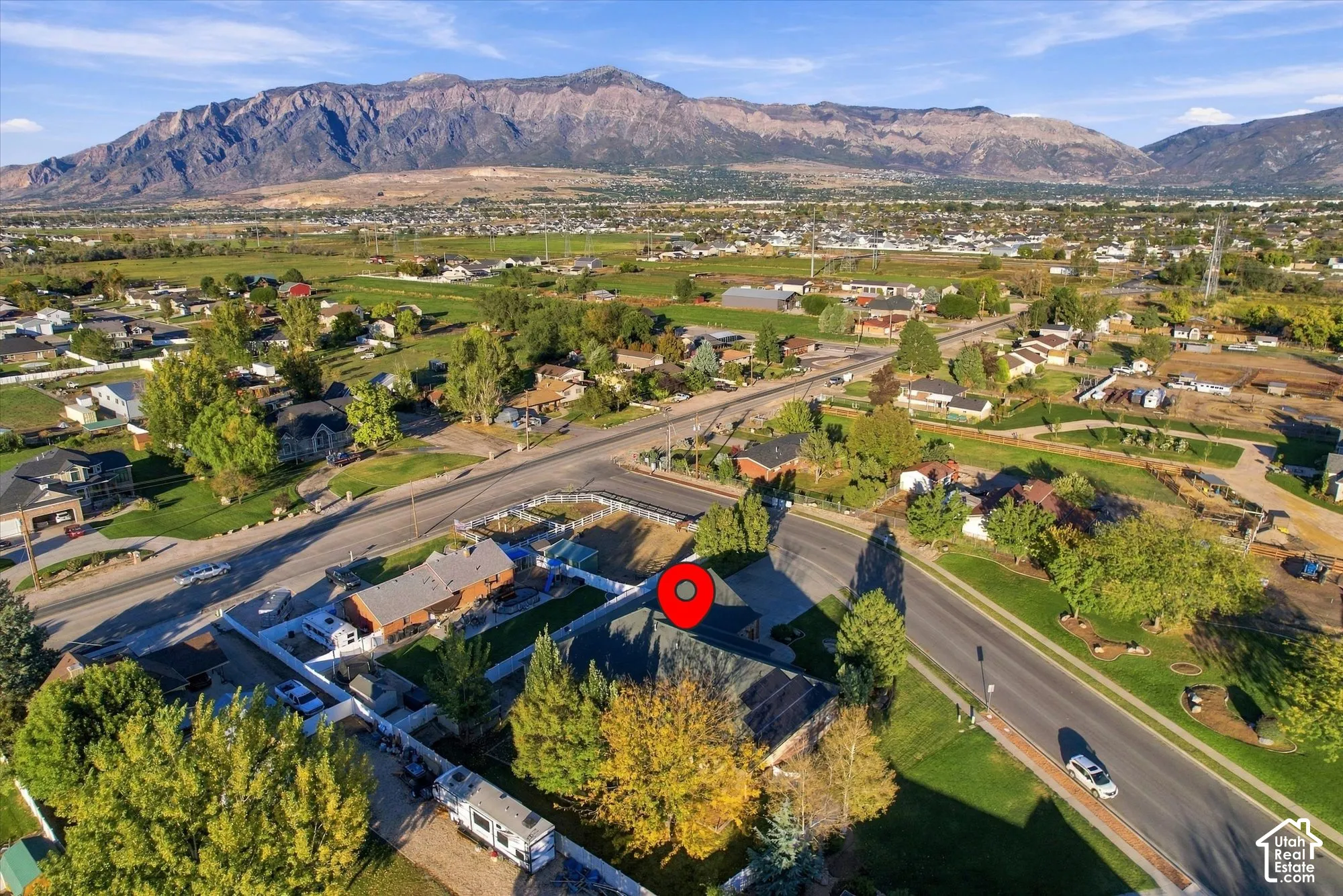 Aerial perspective highlighting a multi-faceted roofline, mature landscaping, paved driveway, and prominent mountain backdrop