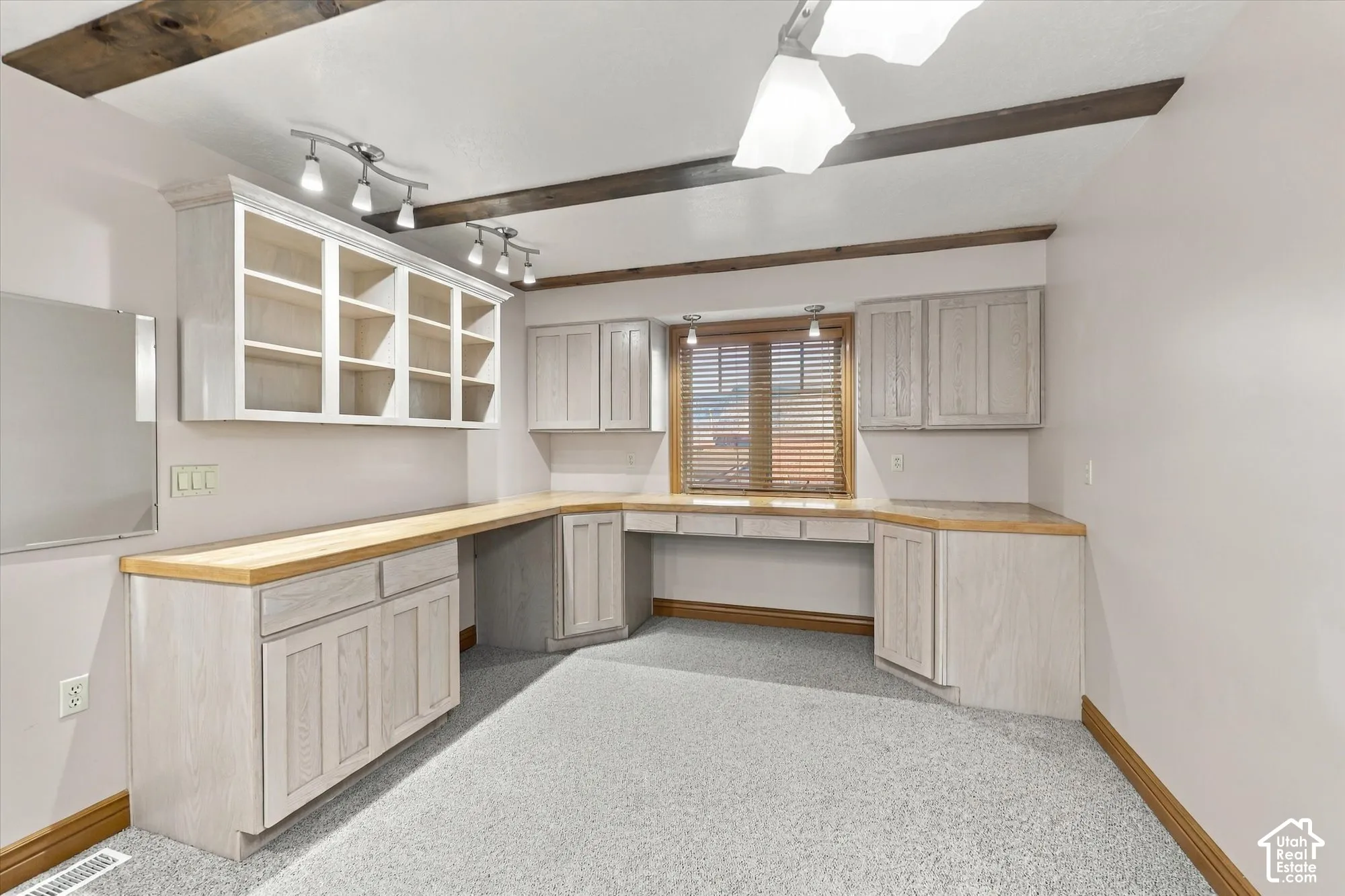 Built-in cabinetry with light wood-finish countertops, exposed decorative ceiling beams, multi-unit track lighting, and a recessed window with integrated shelving