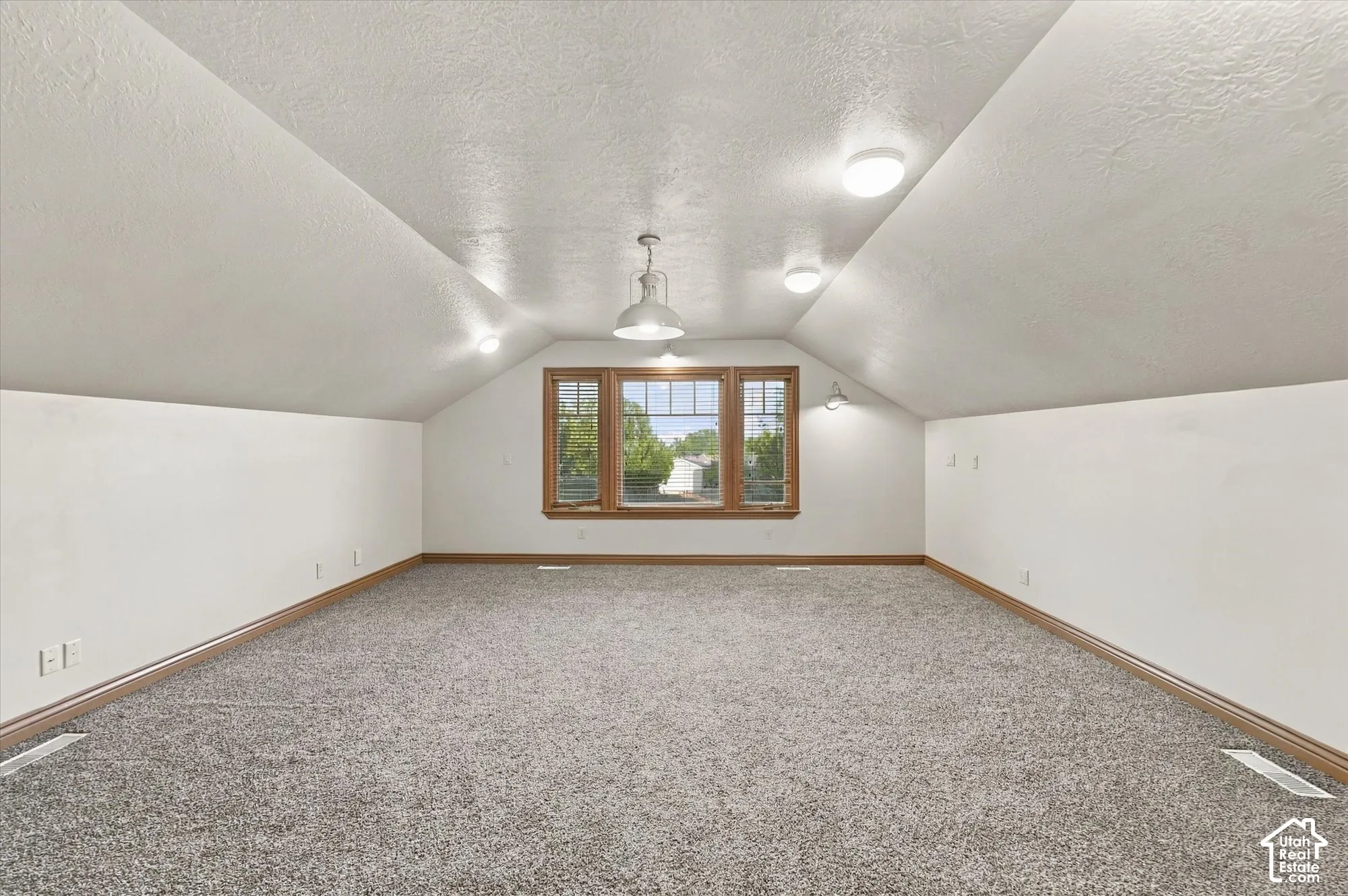 Vaulted ceilings featuring a triple-pane window, neutral carpeting, recessed lighting, and a pendant light fixture