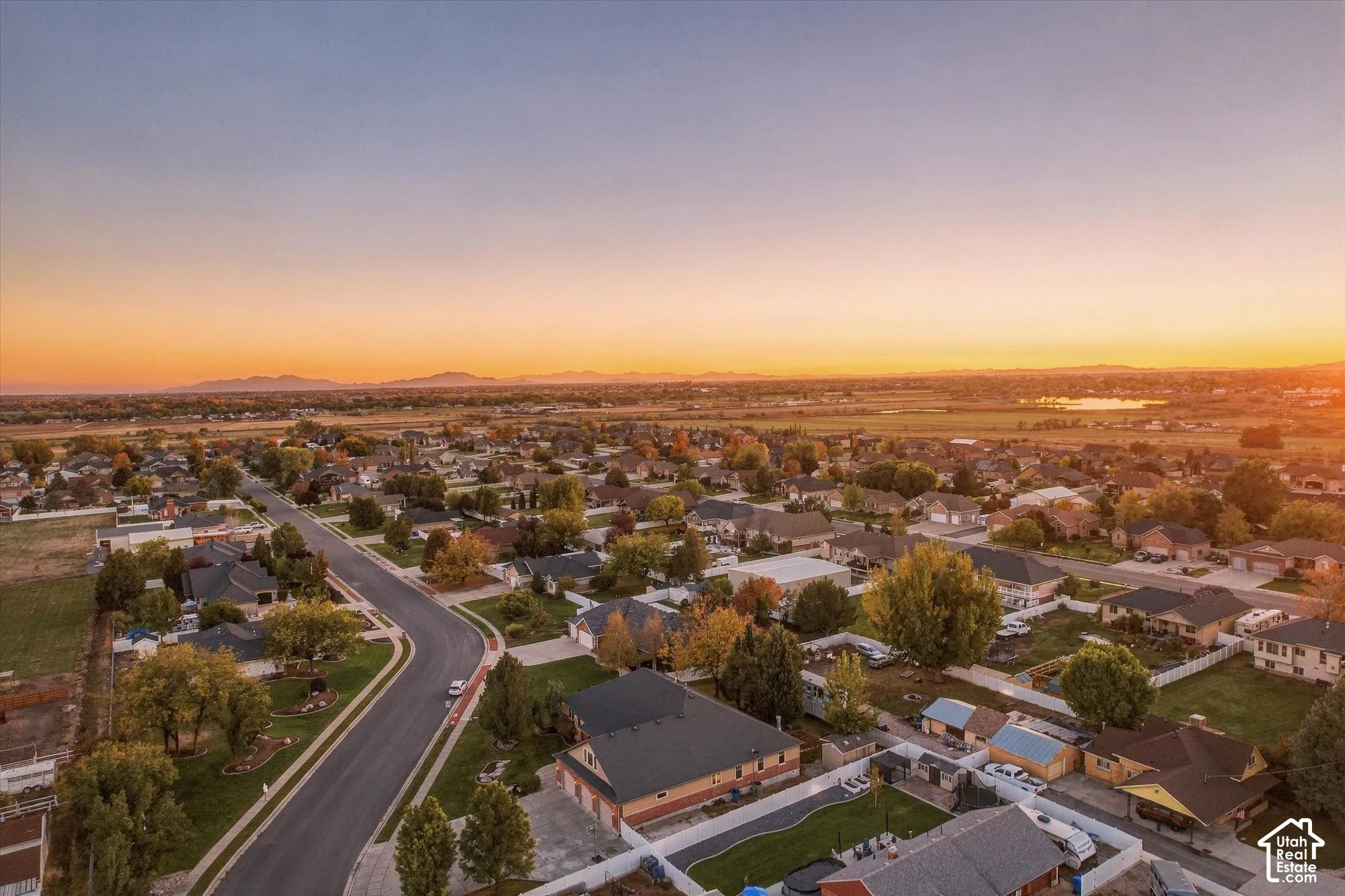 Aerial perspective featuring a suburban neighborhood, mature landscaping, and distant mountain scenery
