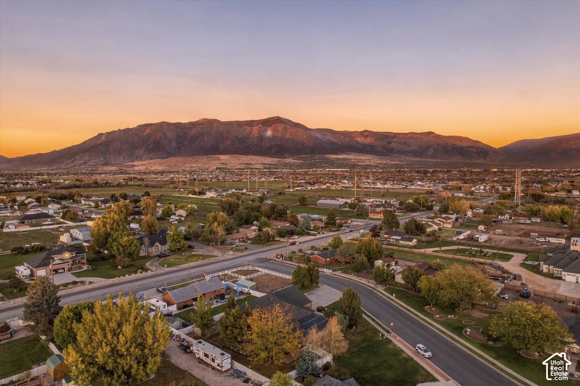 Aerial perspective featuring expansive mountain backdrop, mature trees, and established suburban lot layout