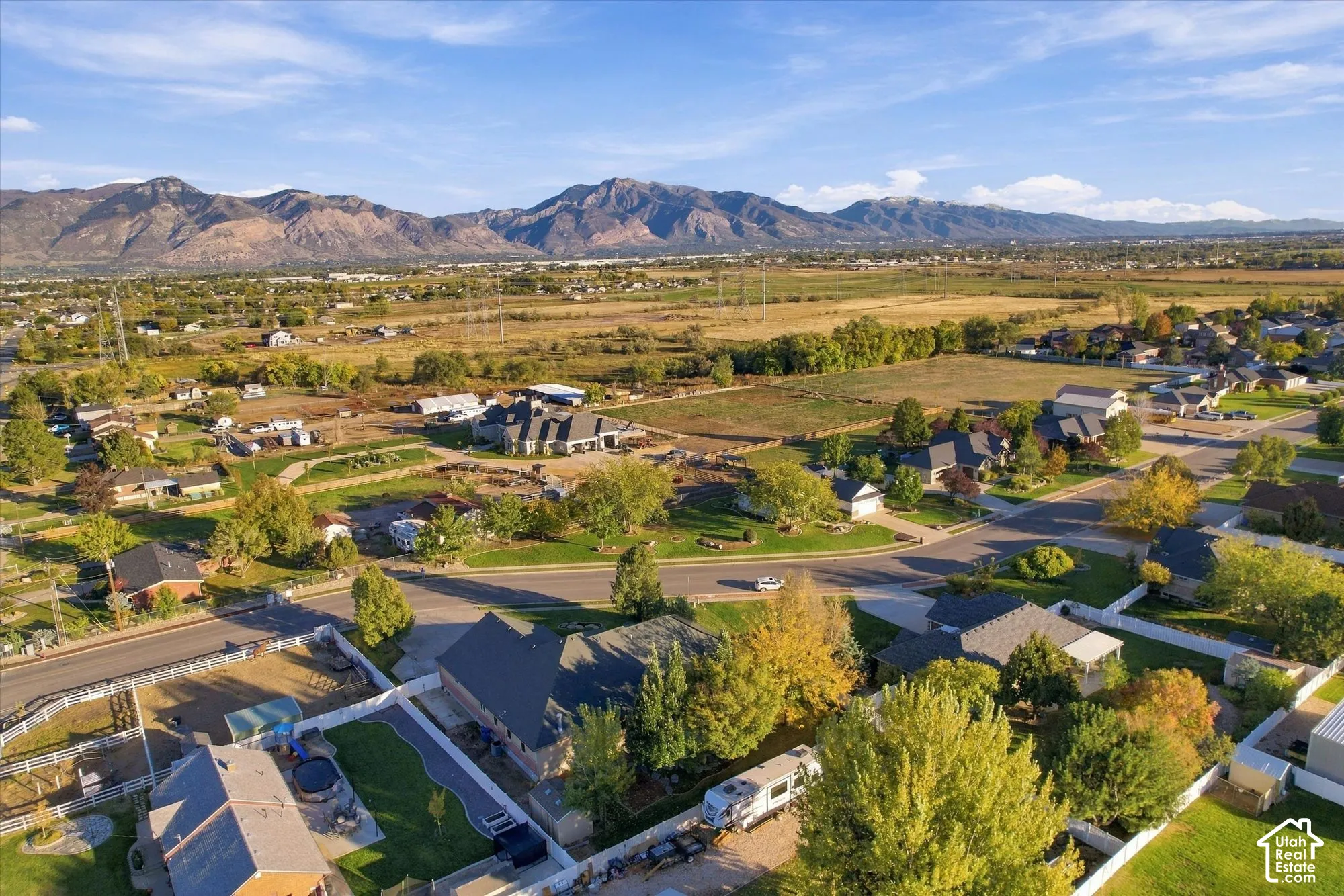 Aerial perspective featuring a residential lot with mountain backdrops, expansive open acreage, and established mature trees