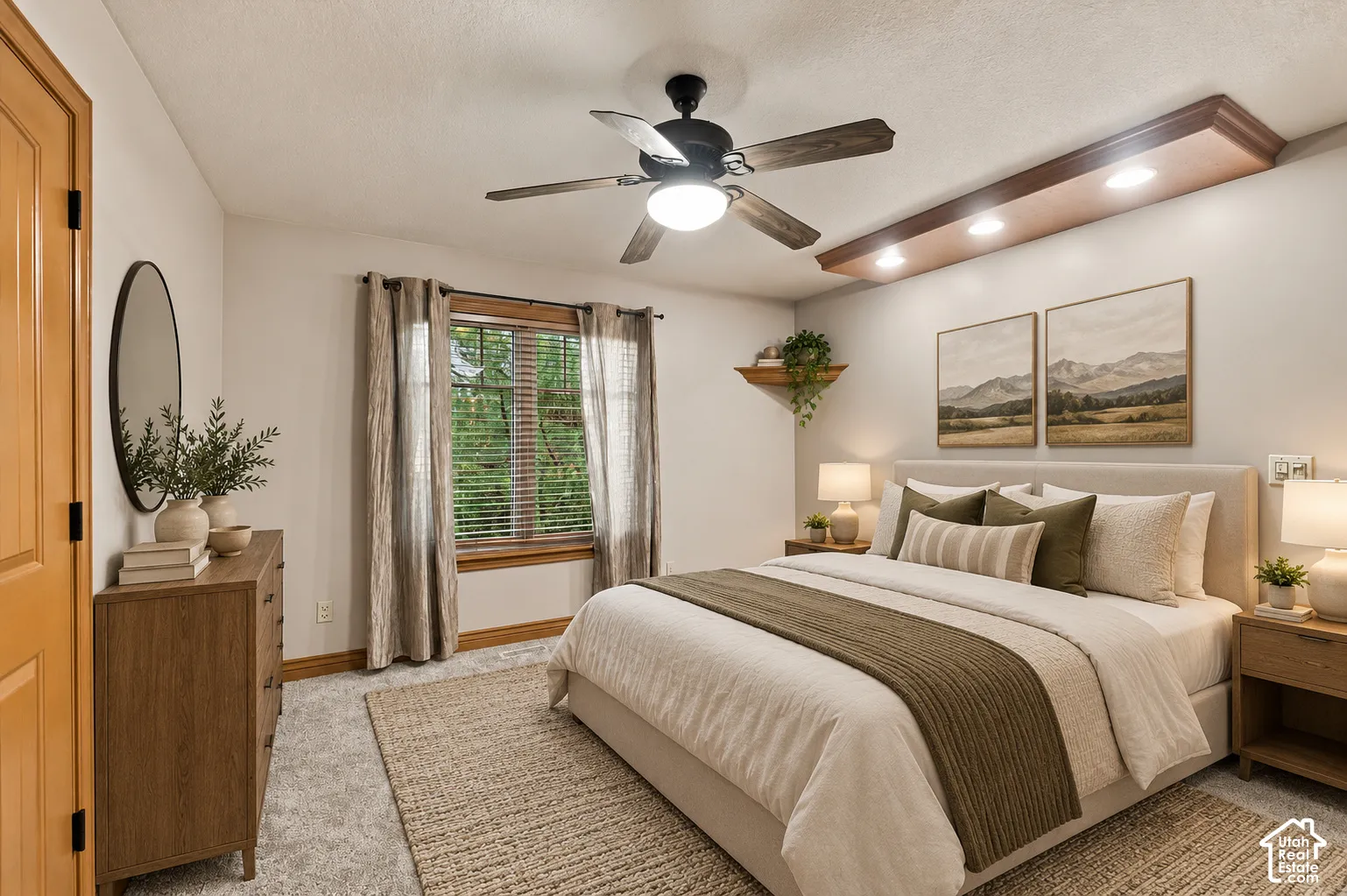 Bedroom featuring a recessed ceiling soffit with integrated lighting, a black ceiling fan, and wood-trim window casing