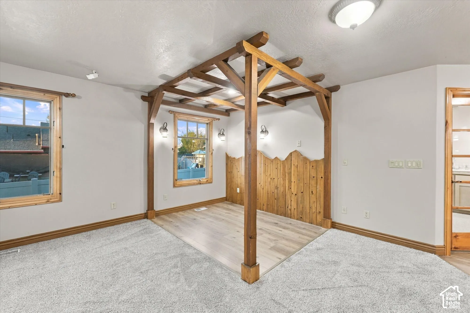 Custom built-in timber pergola, wood-finish flooring, accent wall cladding, multi-pane windows with wooden casing, and wall-mounted sconce lighting