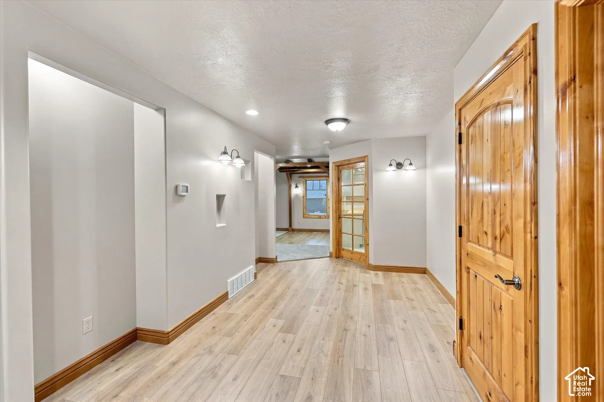 Interior space featuring wood-finish flooring, solid wood doors with arched detailing, recessed lighting, and dual wall-mounted light fixtures