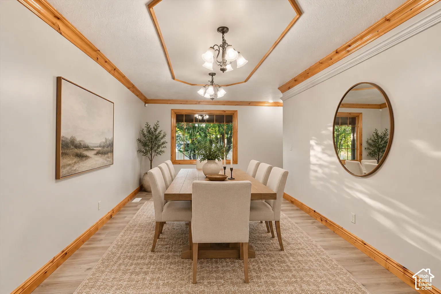 Dining space featuring a hexagonal tray ceiling with crown molding, natural wood-finish trim, multi-bulb pendant lighting, and wood-finish flooring