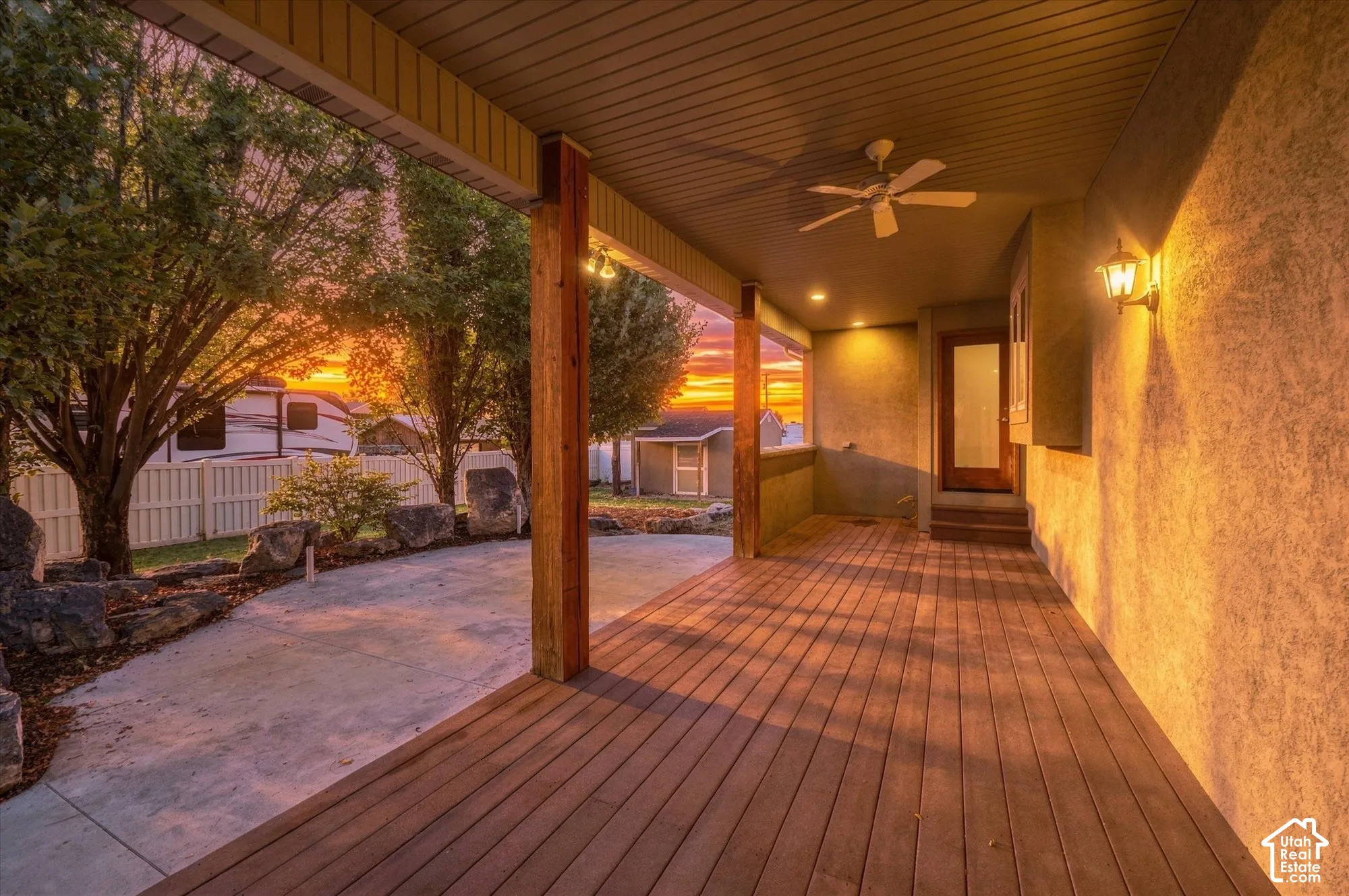 Covered wood-plank deck featuring heavy timber support posts, a ceiling-mounted fan, recessed lighting, and wall-mounted sconces