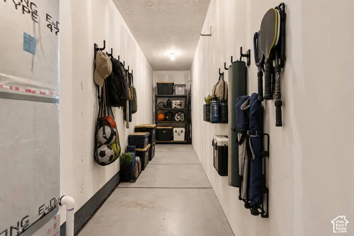 Utility space featuring concrete flooring, drywall finish, and wall-mounted storage hooks