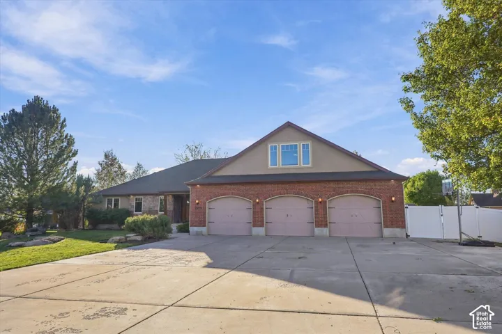 Exterior featuring a brick facade with a three-car garage and concrete driveway