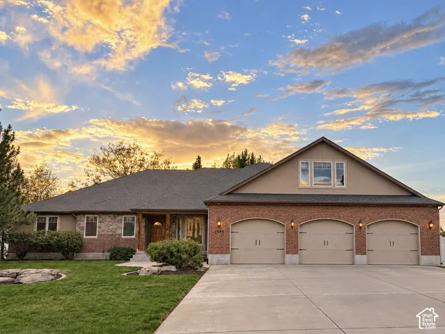 Exterior featuring a combination of brick and stone siding, a three-car garage with arched entrances, a pitched roof, and a paved driveway