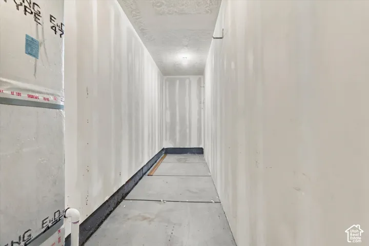 Unfinished utility space featuring concrete flooring and taped drywall panels