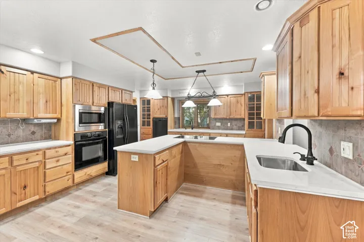 Kitchen featuring natural wood cabinetry, white countertops, built-in stainless steel appliances, a center island, and wood-finish flooring
