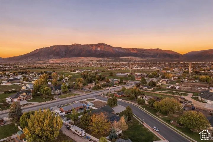 Aerial perspective featuring expansive mountain backdrop, mature trees, and established suburban lot layout