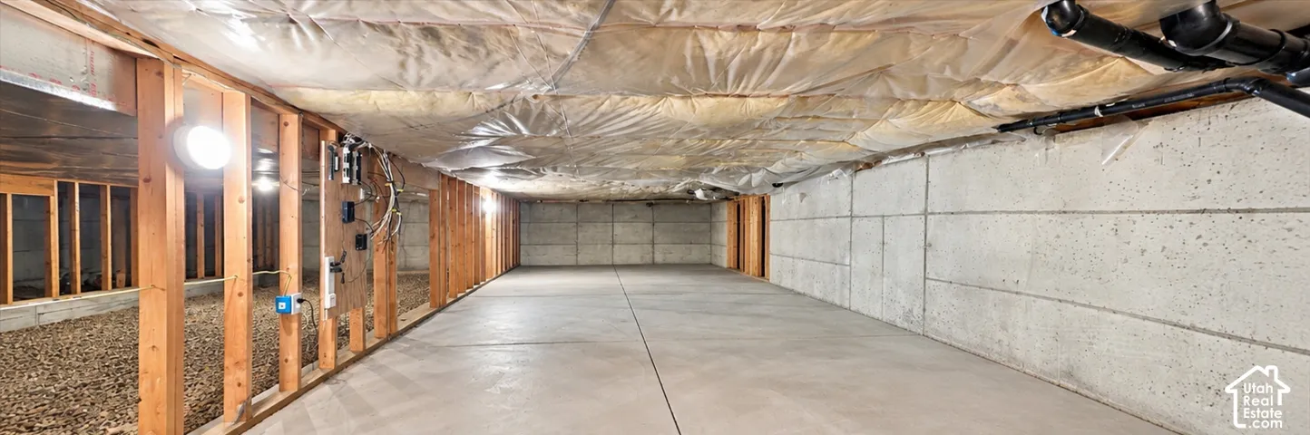 Unfinished basement featuring concrete foundation walls, a poured concrete floor, exposed timber framing, and vapor-barrier ceiling insulation