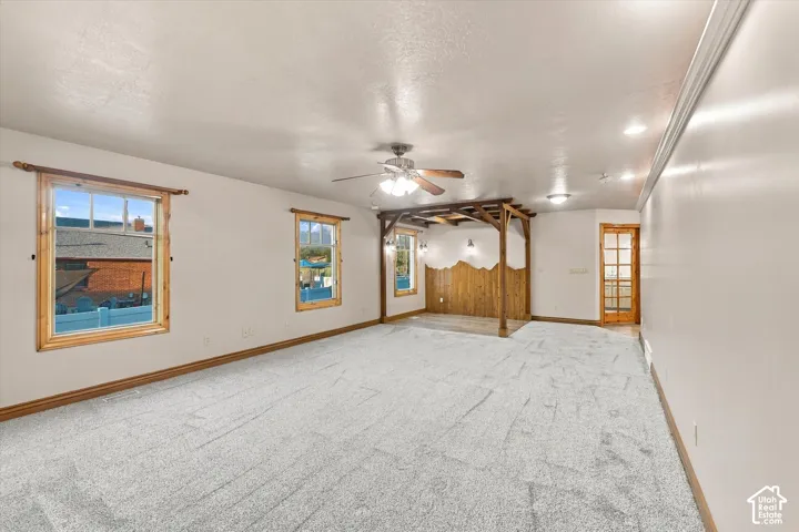 Spacious room featuring carpeting, wood-trimmed windows, a built-in wooden architectural partition, and a French-style door