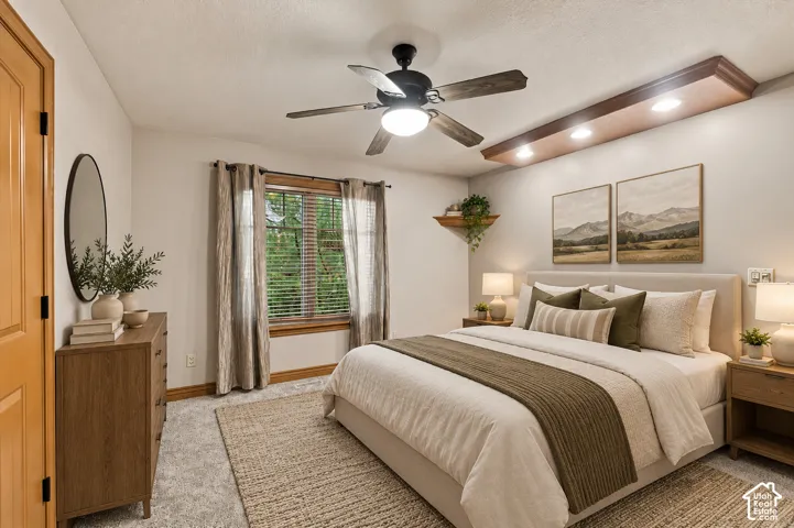 Bedroom featuring a recessed ceiling soffit with integrated lighting, a black ceiling fan, and wood-trim window casing
